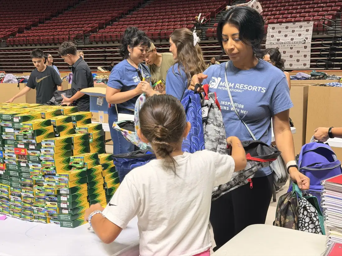 A volunteer helping a student choose a backpack.